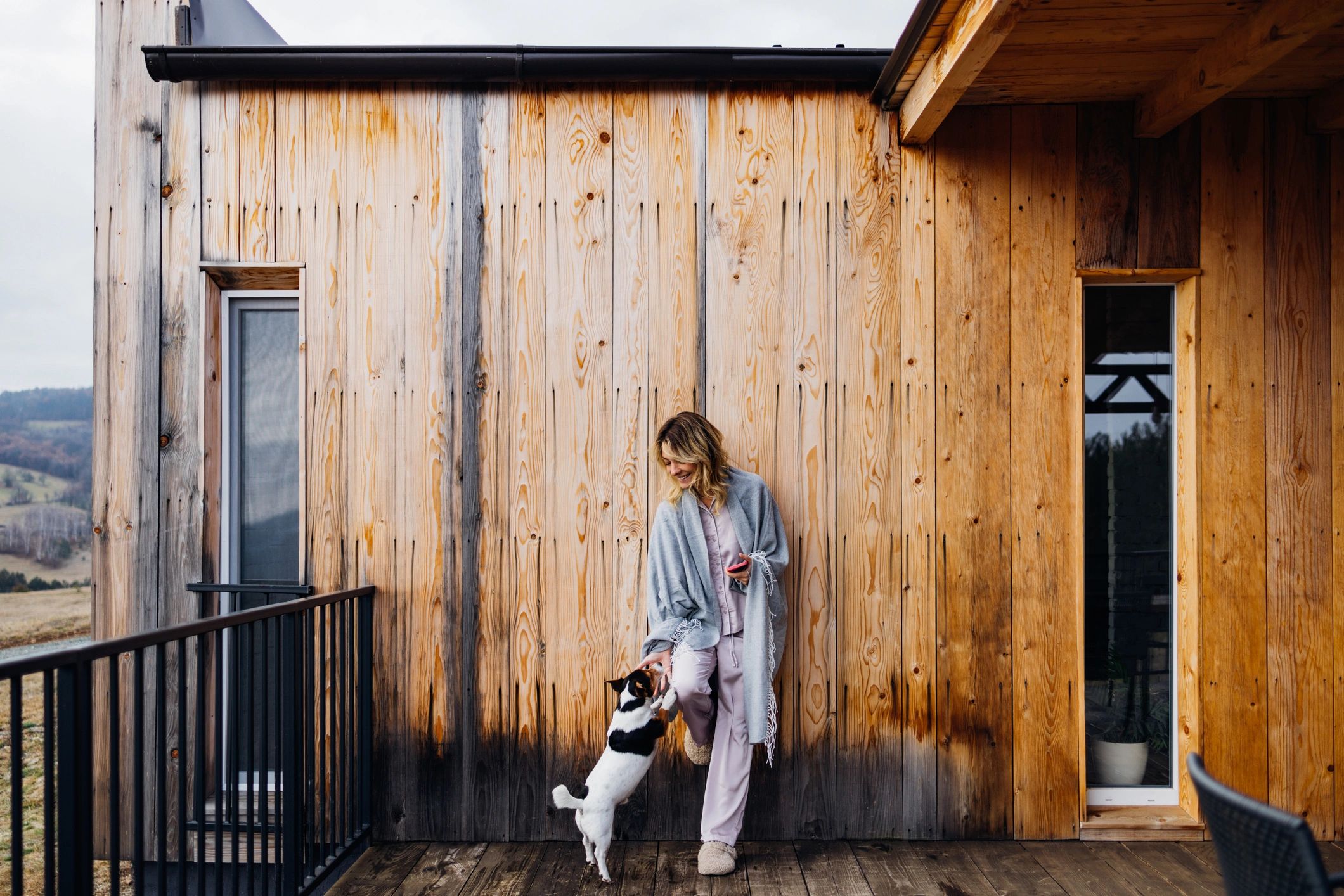 Woman smiling with puppy while using a smartphone